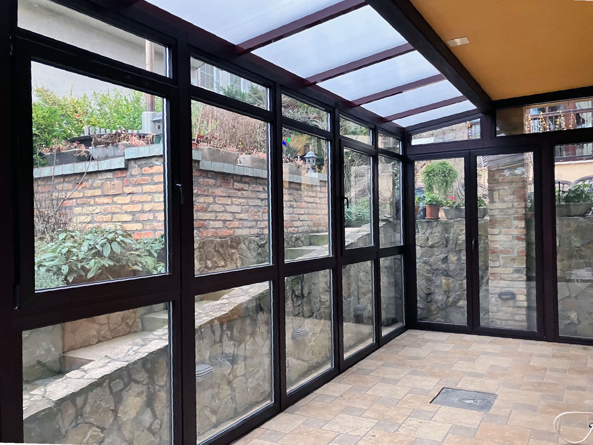 Barna fa hatású télikert belső tere nagy üvegfelülettel tolóajtóval üresen