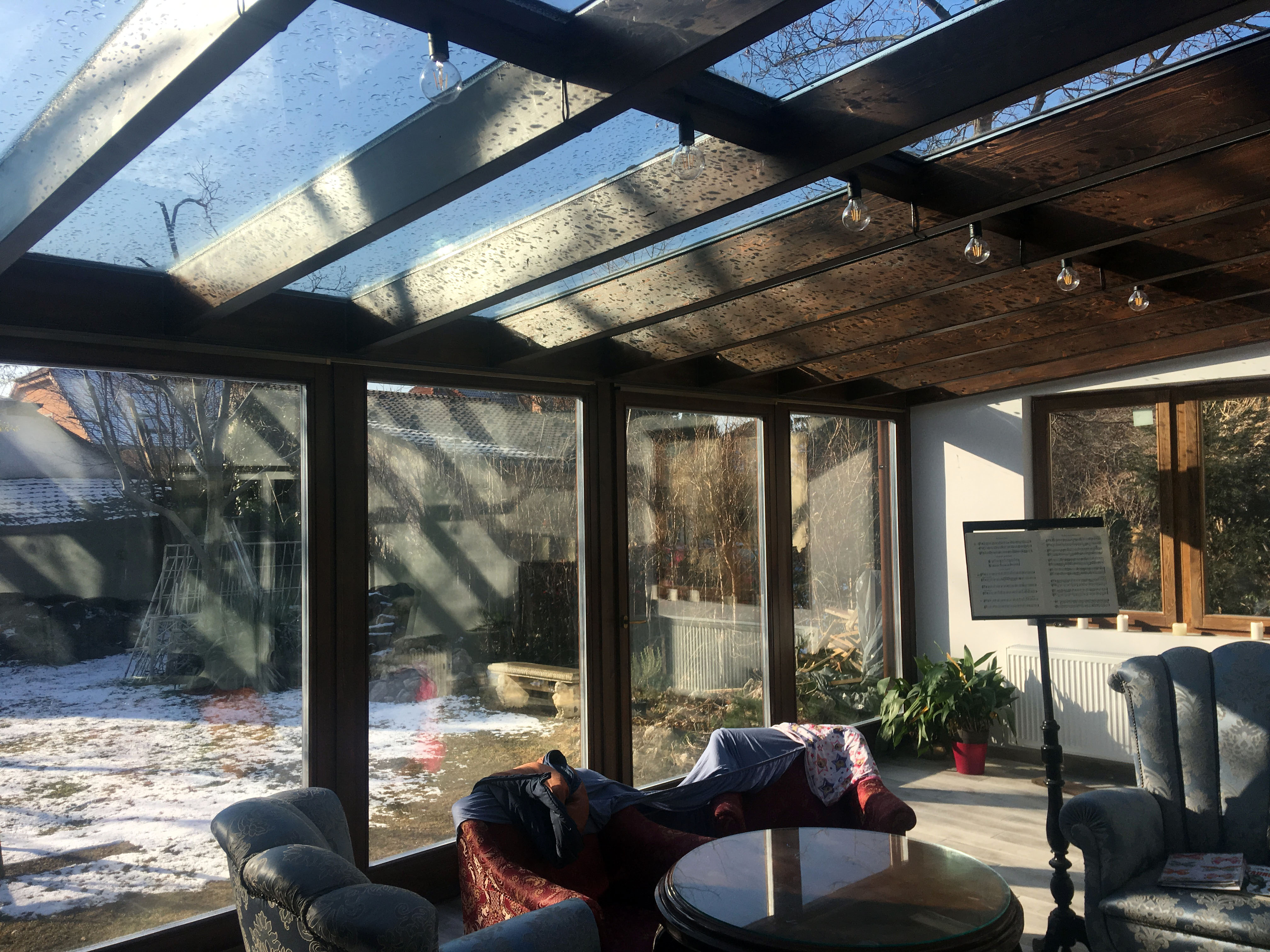 Barna fa hatású télikert belső tere nagy üvegfelülettel tolóajtóval ülőgarnitúrával