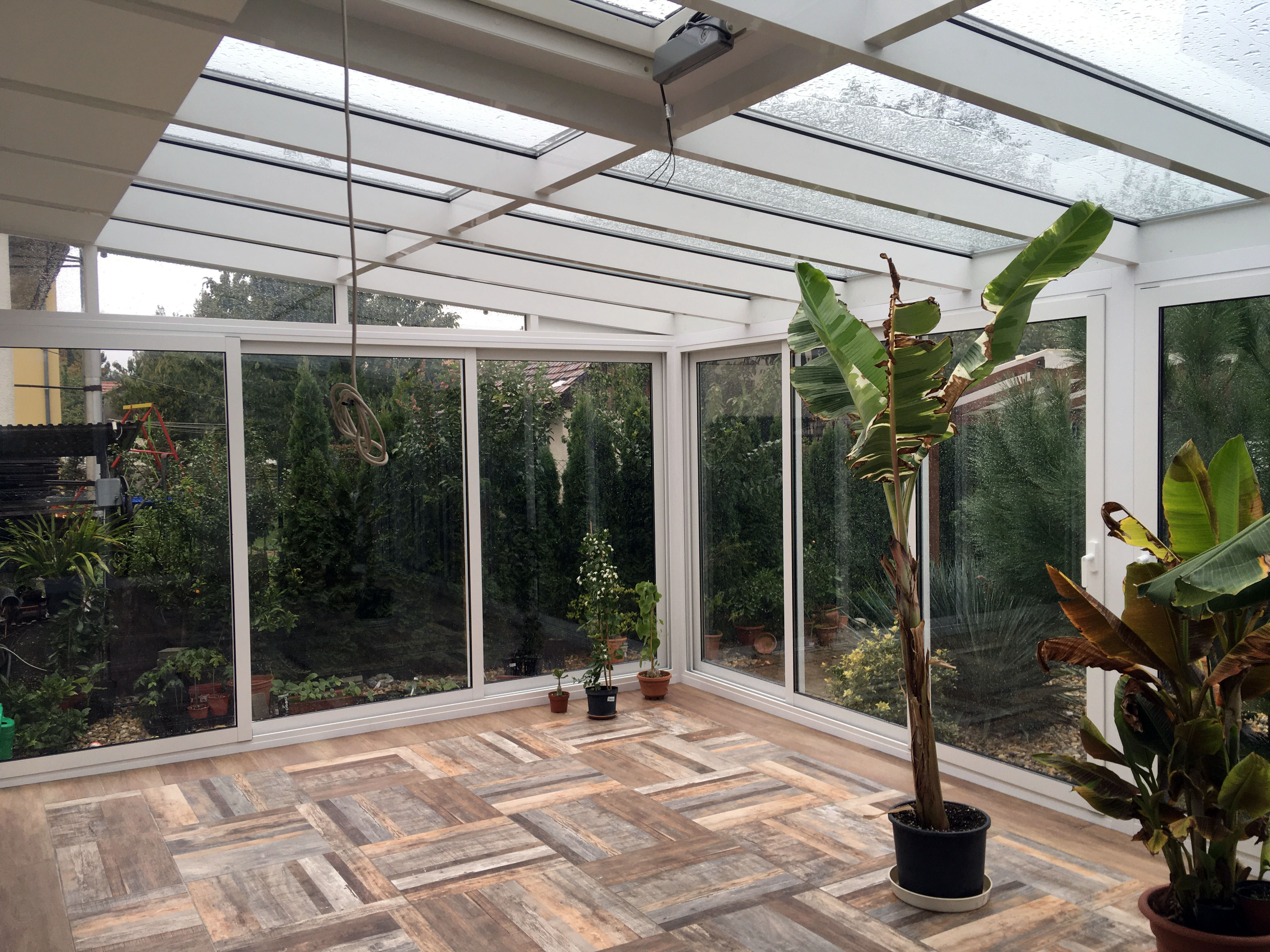 Fehér télikert belső tere növényekkel nagy üvegfelülettel