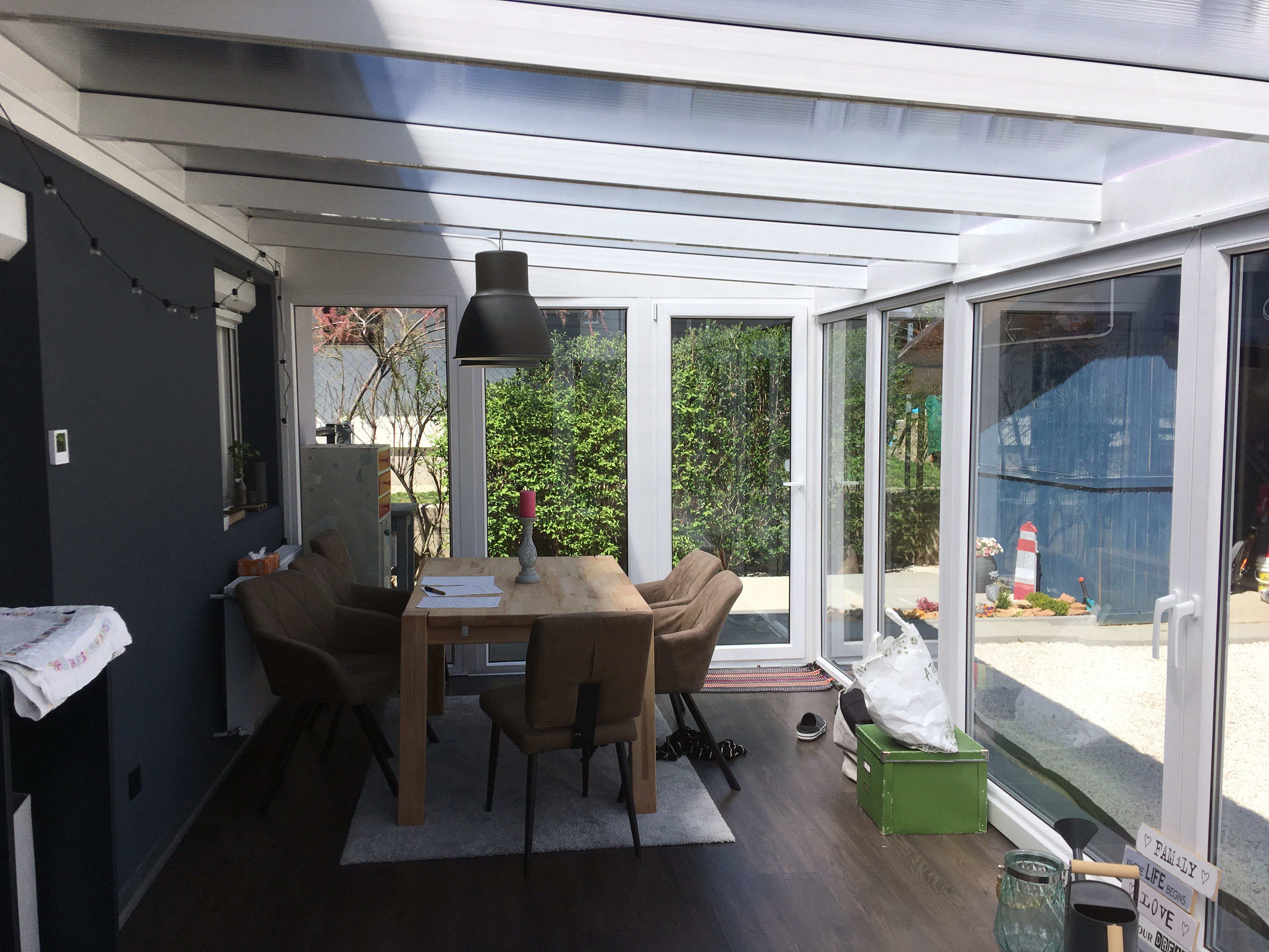 Fehér modern télikert belső tere barna fa hatású ülőgarnitúrával nagy üvegfelülettel