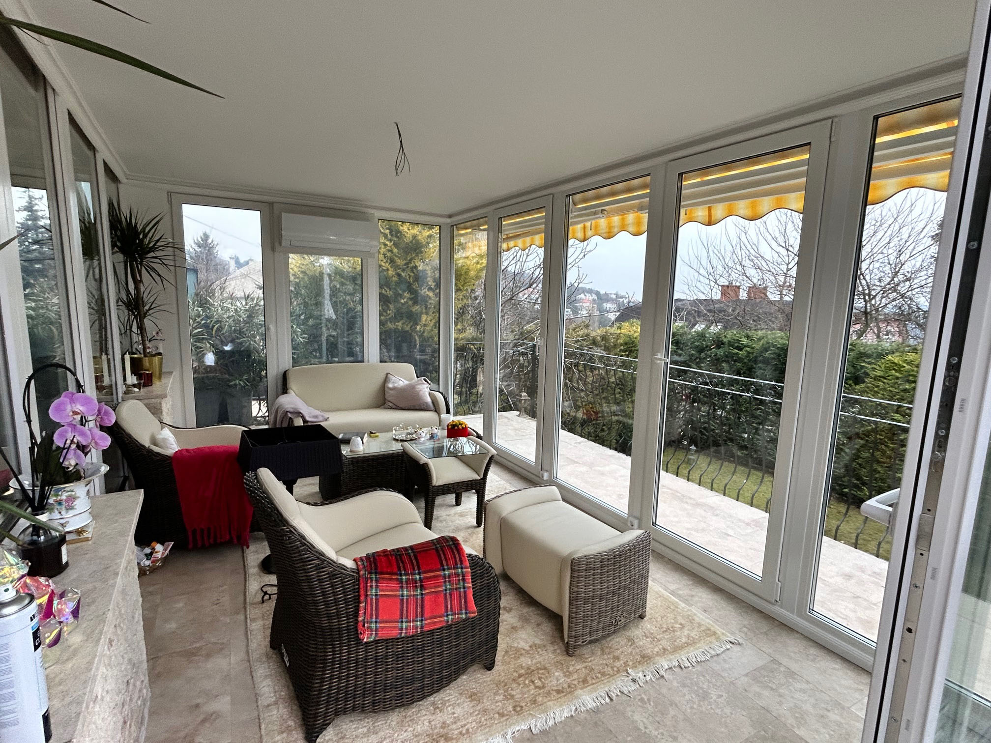 Modern fehér télikert belső tere egy fa hatású ülőgarnitúrával