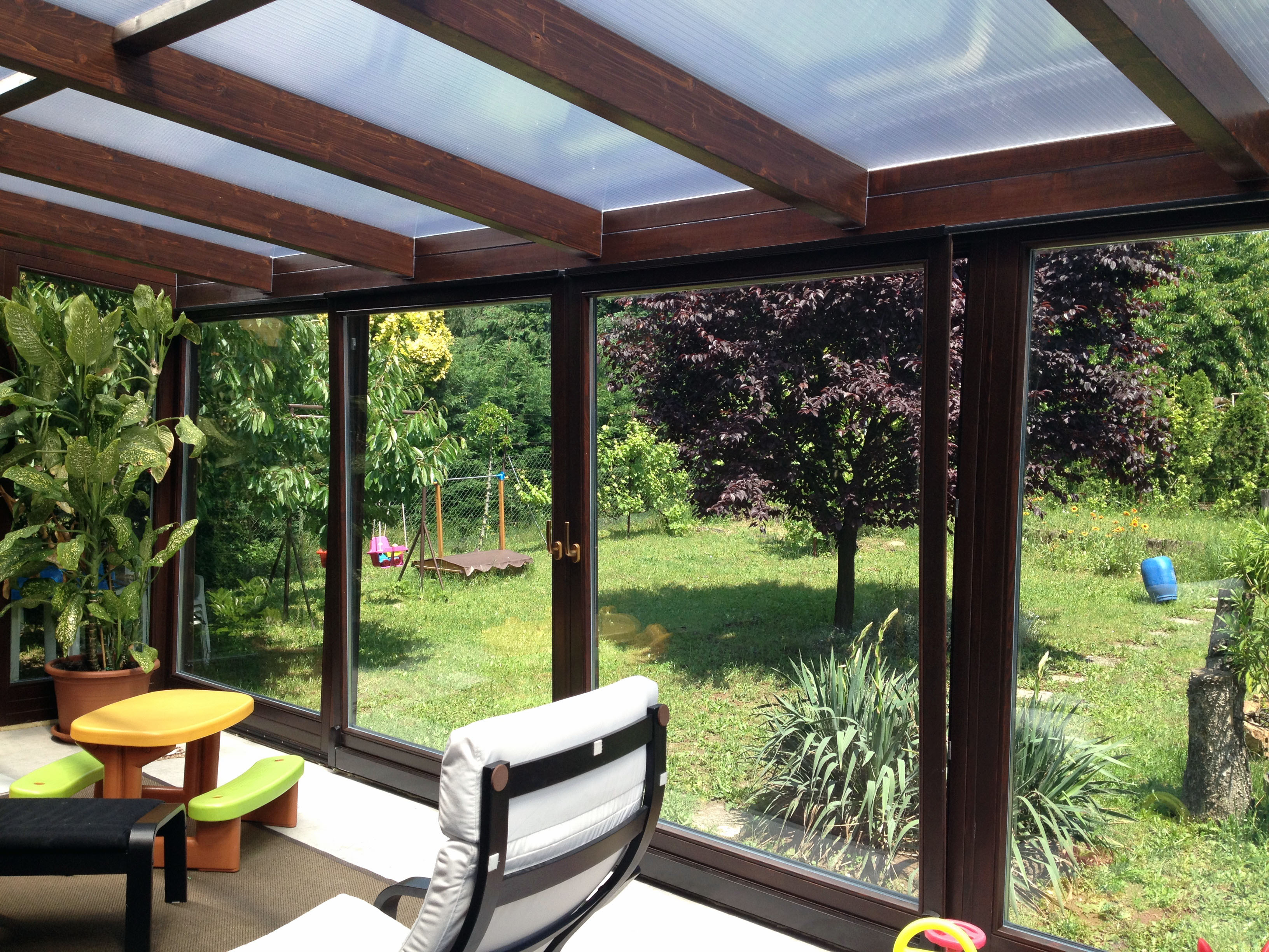 Fa hatású nagy üvegfelületes lakótélikert belső tere egy székkel