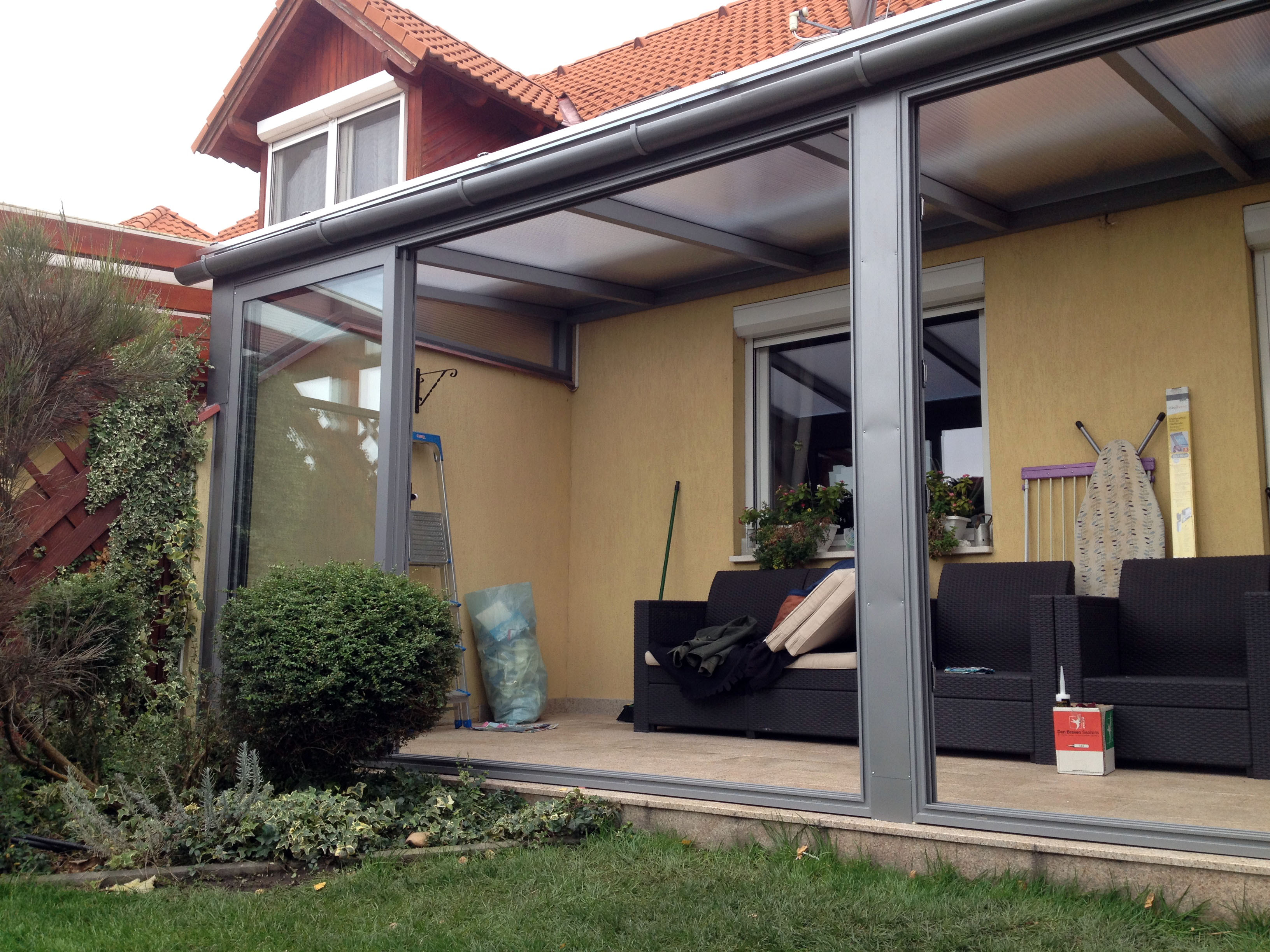 Nyitott terasz kanapéval és üvegezett tetővel